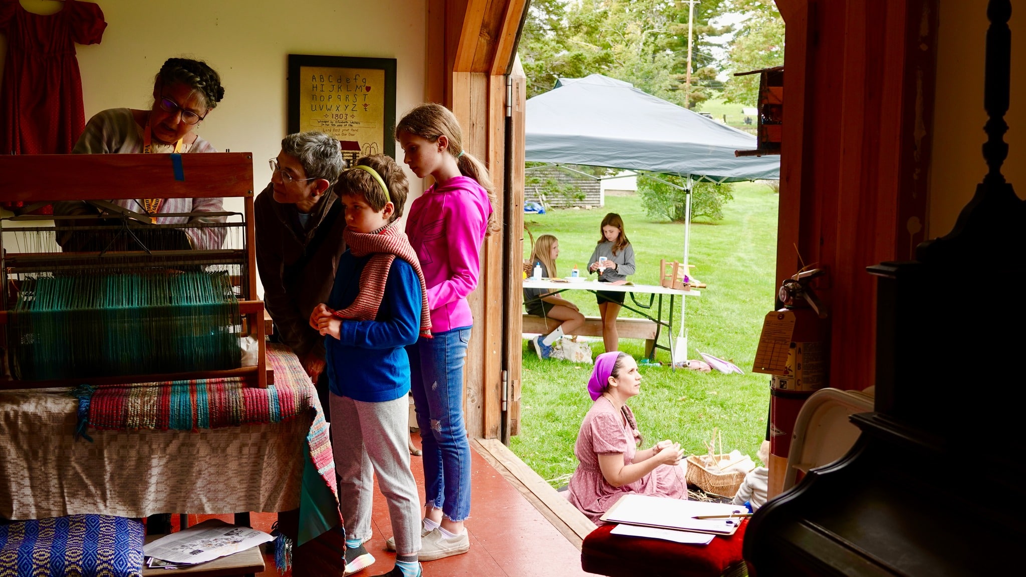 Fiber Faire photo with family looking at loom.